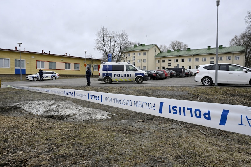 A police line running along the permiter of a land area with buildings and cars in the distance 