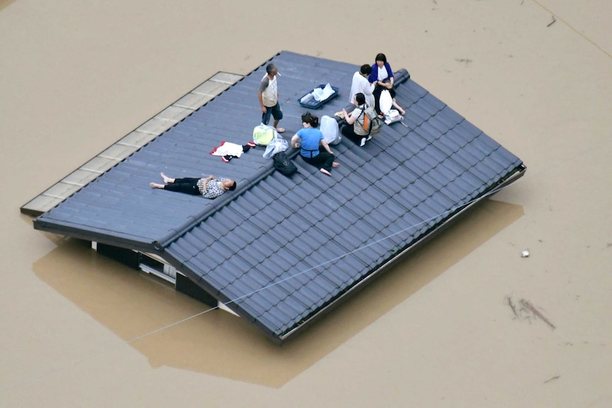 People wait to be rescued on the top of a house in Kurashiki.