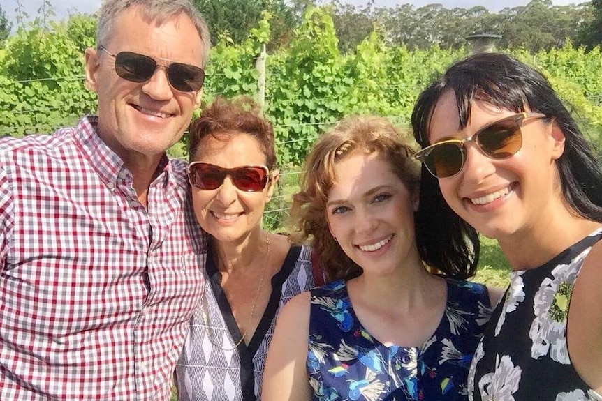 The Falkholt  family stands close together while smiling.