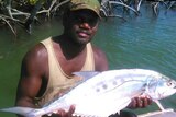 A photo of Tiwi Bombers footballer holding a large fish.