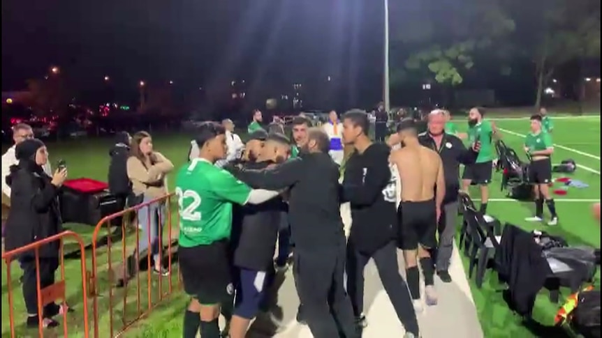 a man being held back by a group of people on a soccer field