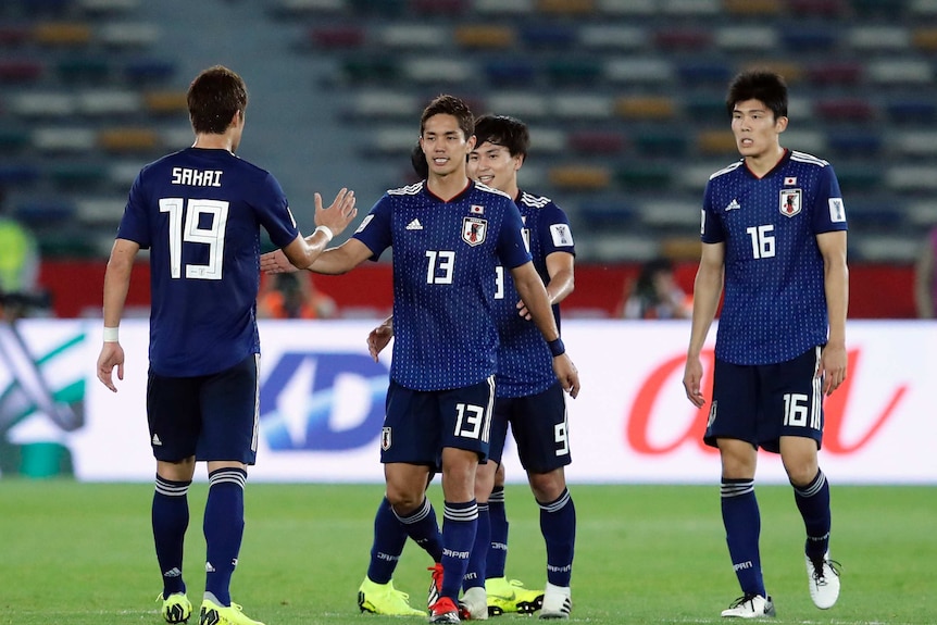 Wearing blue, Japanese players shake hands after winning a match.