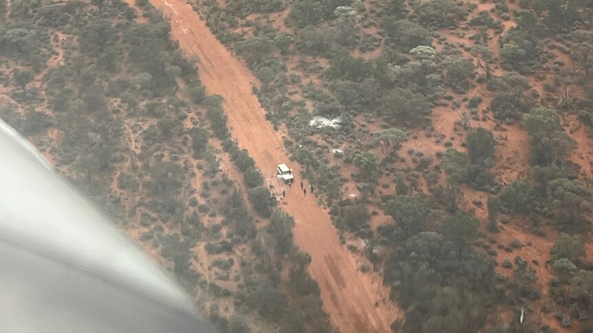 The view through a plane window of people bogged on an outback road.