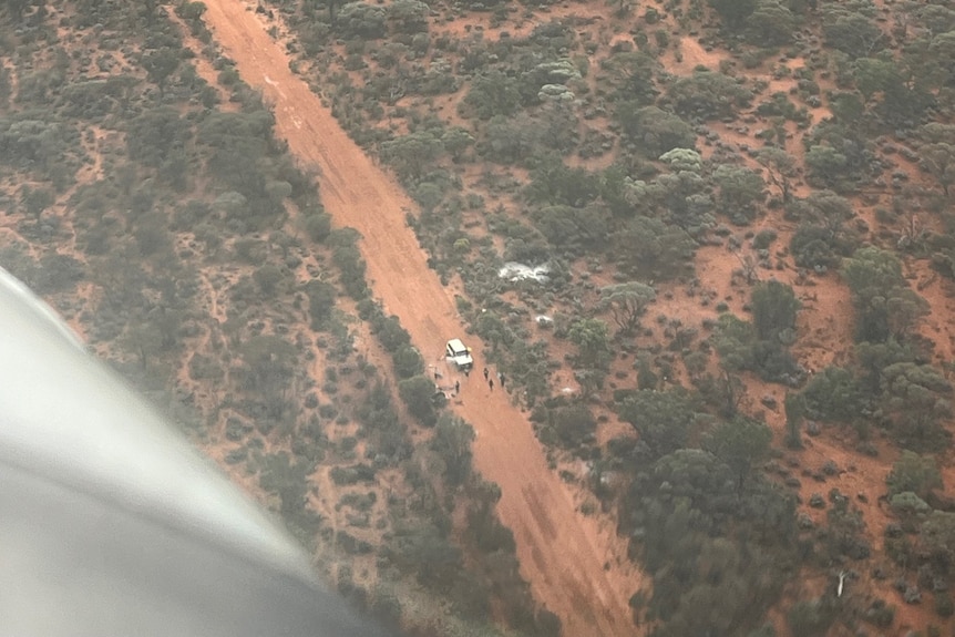 The view through a plane window of people bogged on an outback road.