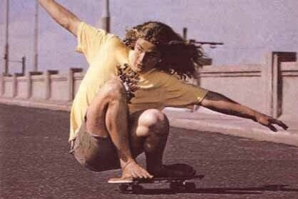man in shirt with hair on skateboard