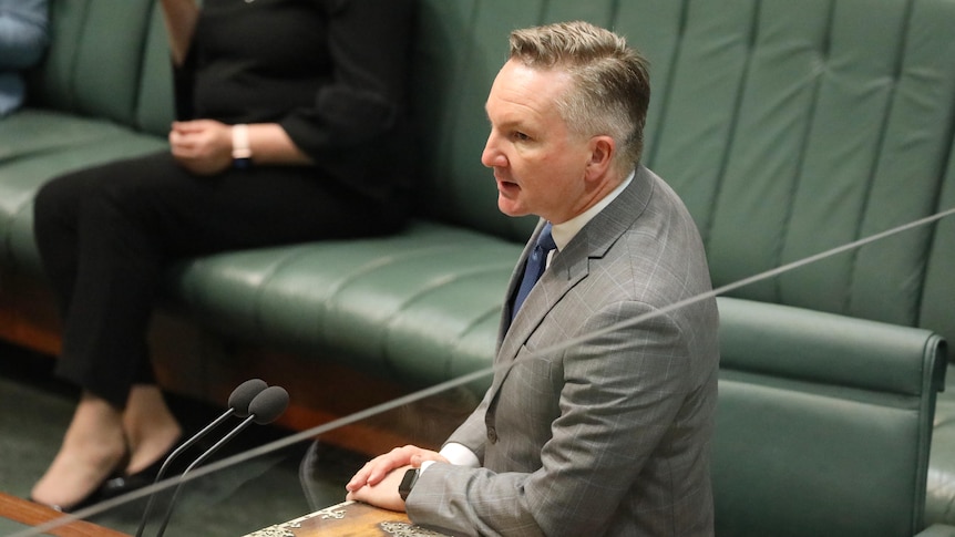 Bowen stands with his arms leaning on the despatch box on the lower house floor as he speaks.