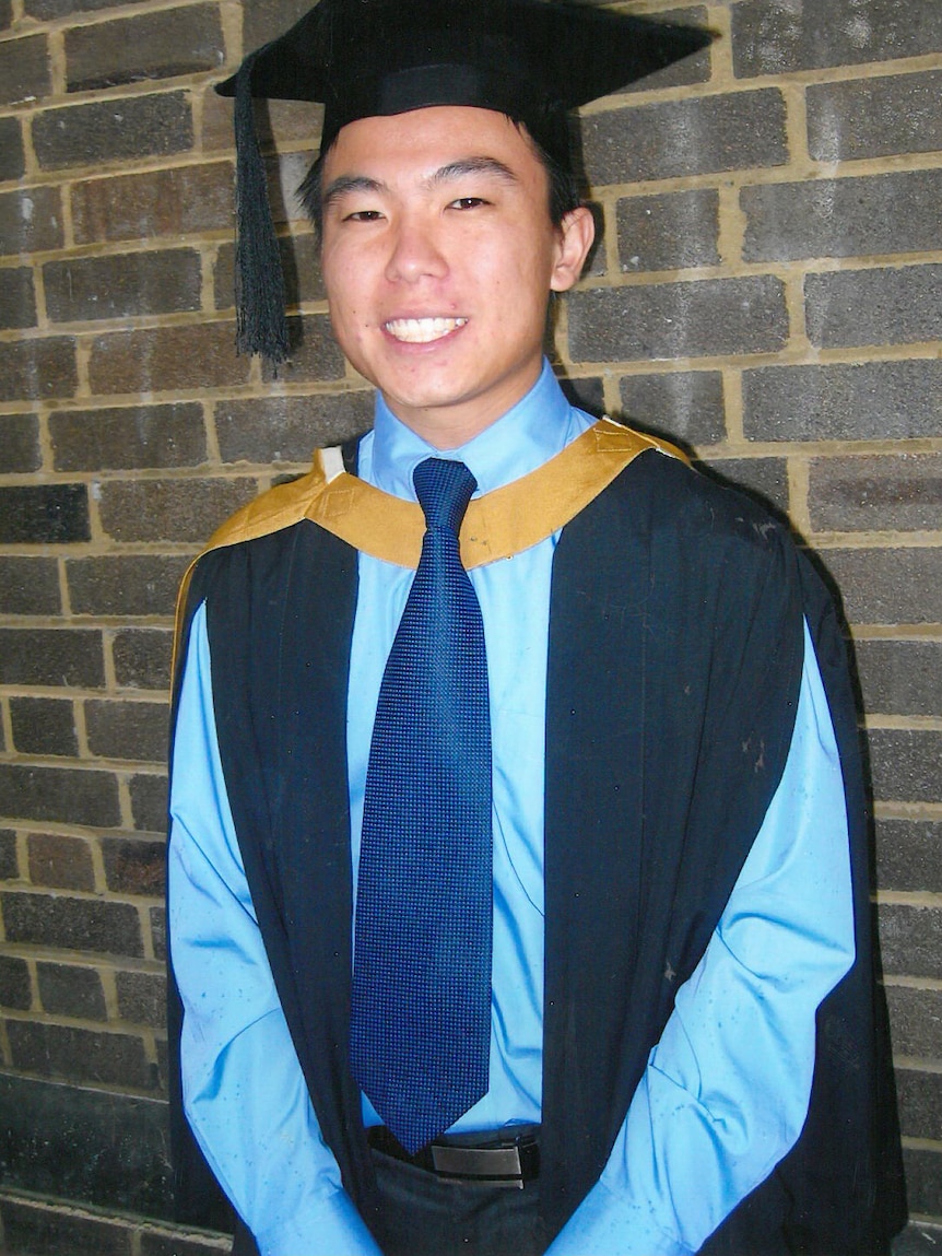 Young man in blue shirt and graduation cape and cap. 