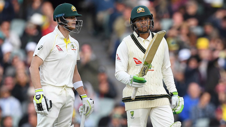 Usman Khawaja raises his bat after reaching a half-century as Steve Smith looks on at Adelaide Oval.