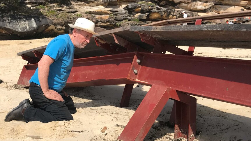 Sculptor Michael Snape inspects his artwork that has been partially buried by sand