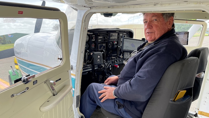 A man sits in the cockpit of a small plane.