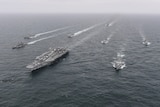 A series of naval ships in formation in the sea. 