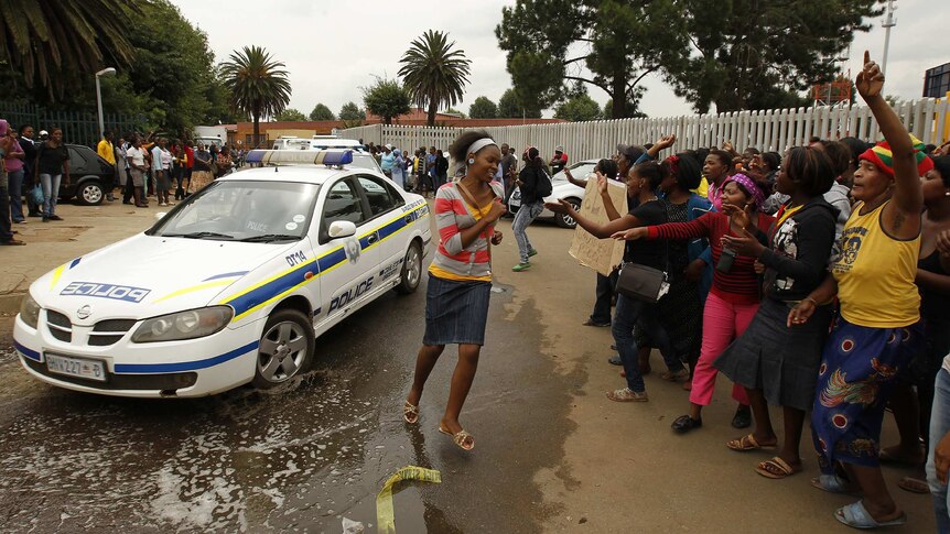 Protesters gesture at South African police car