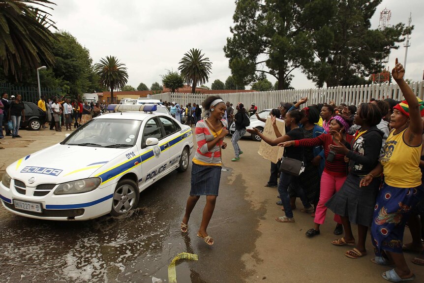Protesters gesture at South African police car