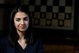 Portrait of woman Sara Khadem with a chessboard behind her. 