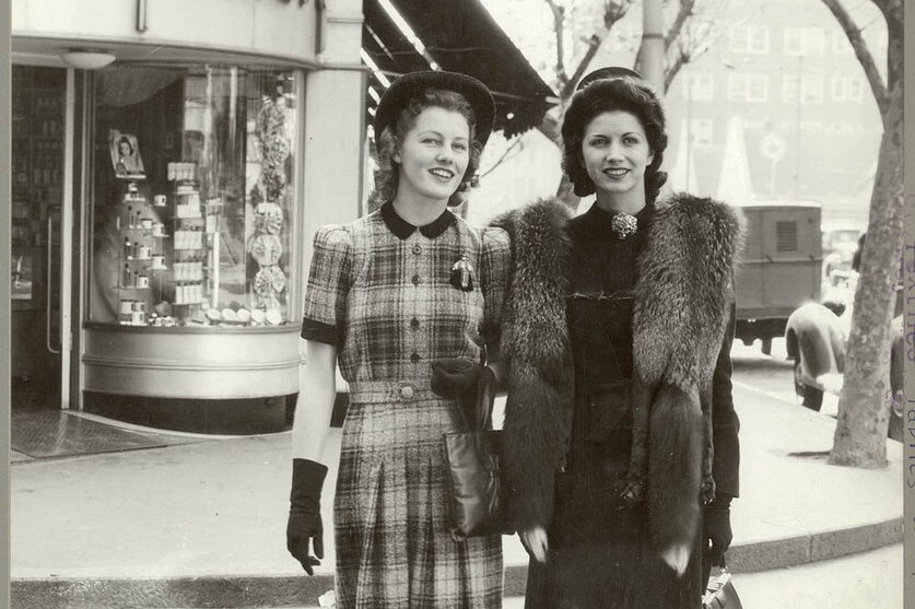 Two models cross the street near Gregory's shop in the year 1941.