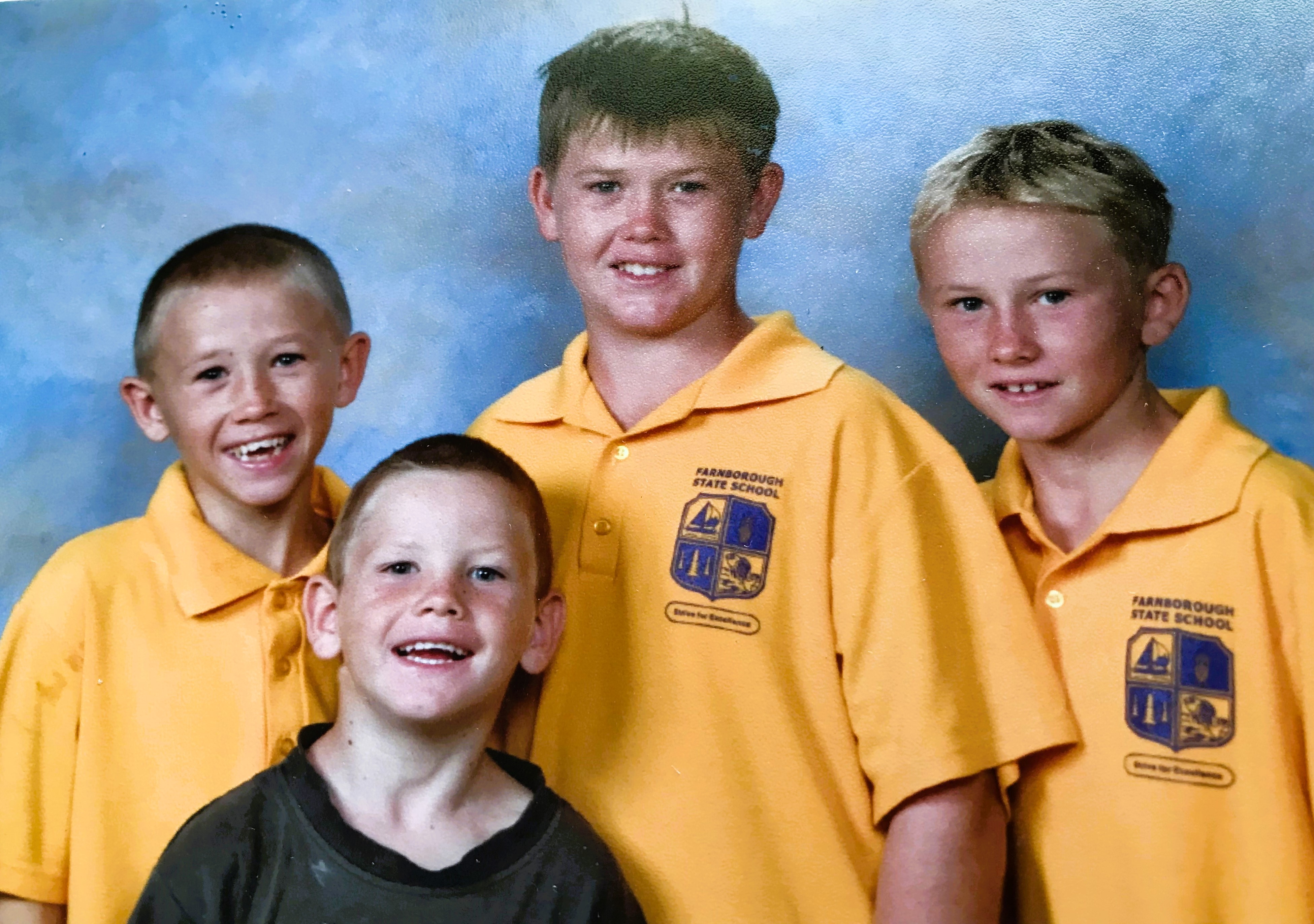 A family photo of four boys in a yellow school uniform.