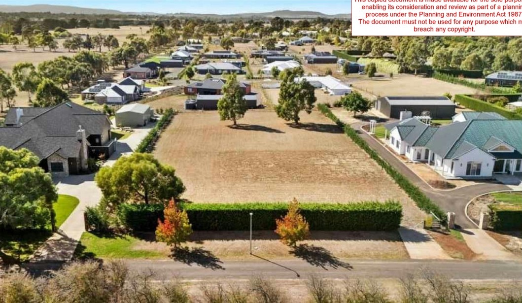A plot of land sits before houses in the background in a new estate