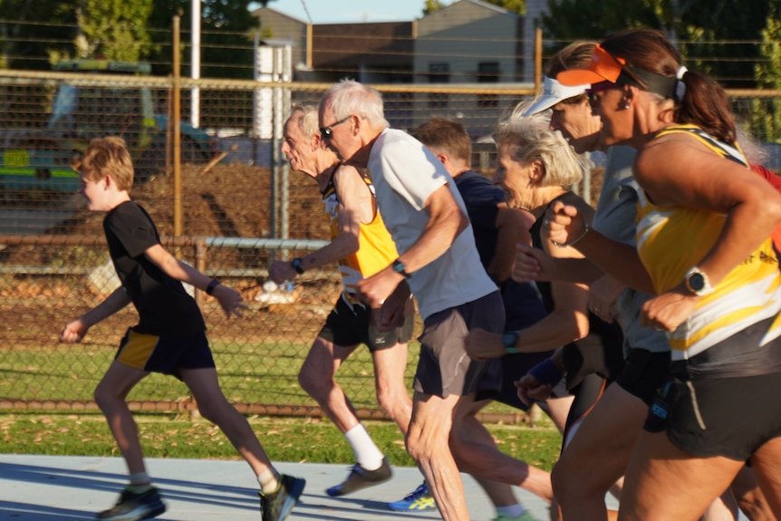 Several older people run on a track.