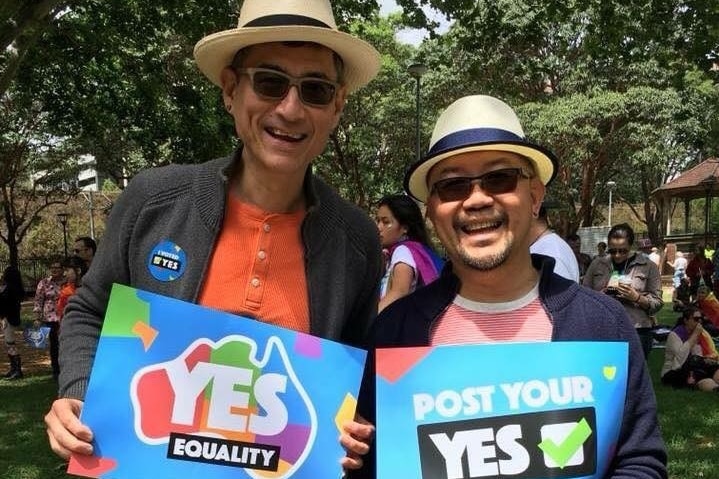 Two men holding "Yes" signs at a marriage equality event