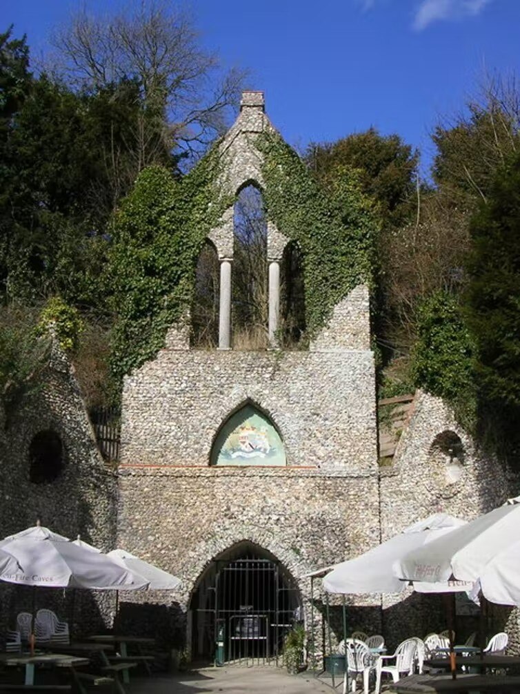 The entrance to a cave, with an ornate church-like gate covered in vines