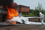 Man in a suit putting out a fire with white foam.