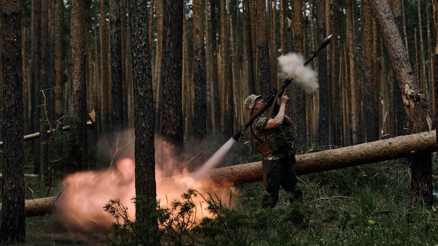 A Ukrainian soldier fires an RPG in a forest area.