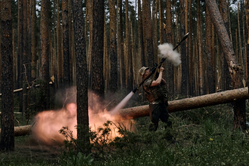 A Ukrainian soldier fires an RPG in a forest area.