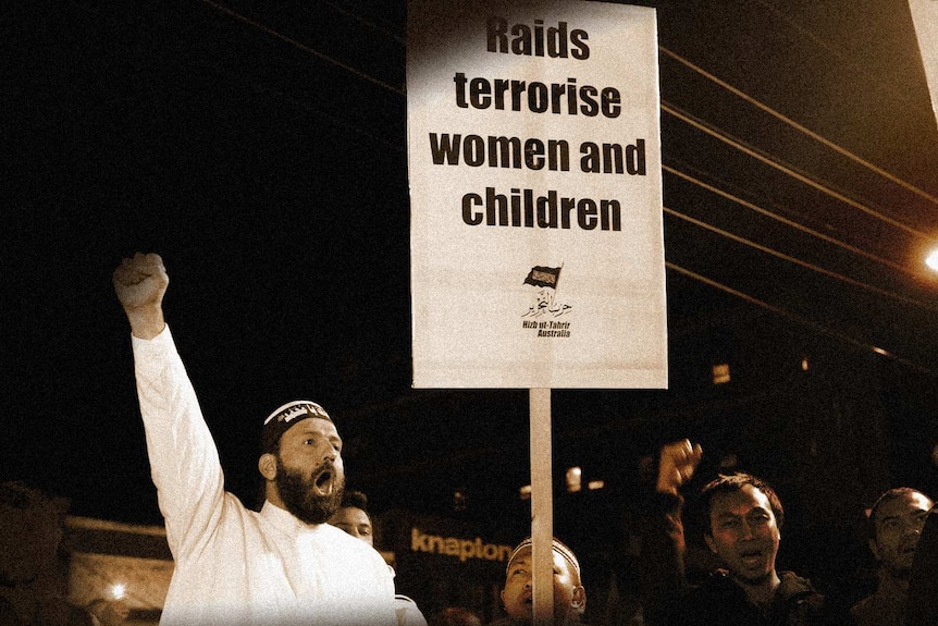 Monis at a protest with his fist in the air next to size that reads 'raids terrorise women and children'