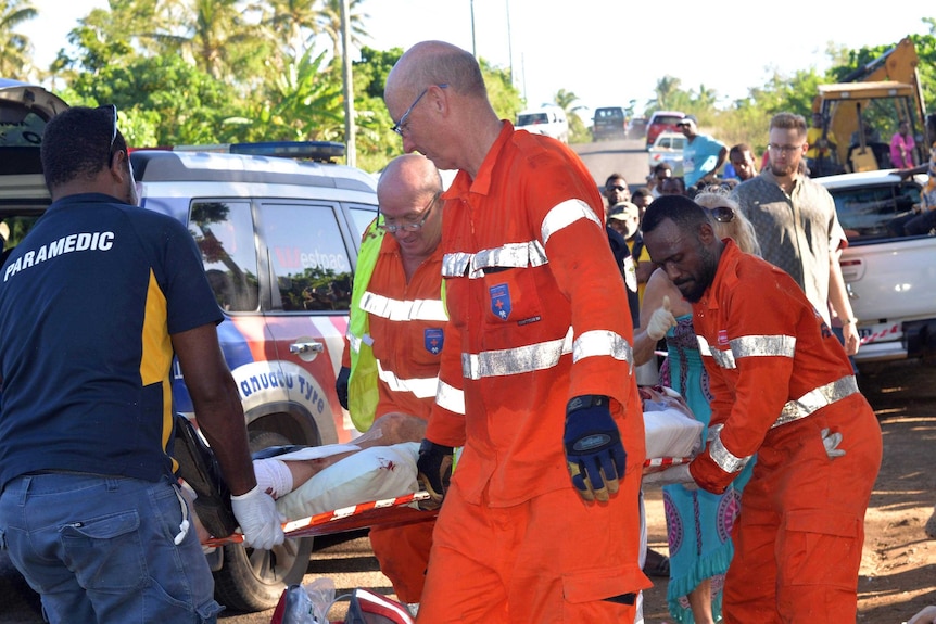 Emergency services personnel carry a passenger on a stretcher.