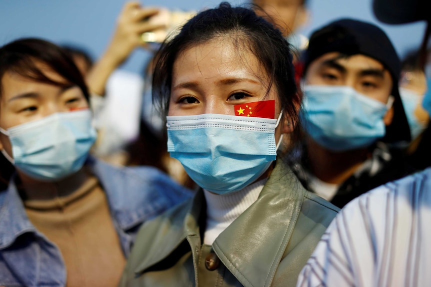 A young woman in a face mask with a Chinese flag tattoo on her cheek