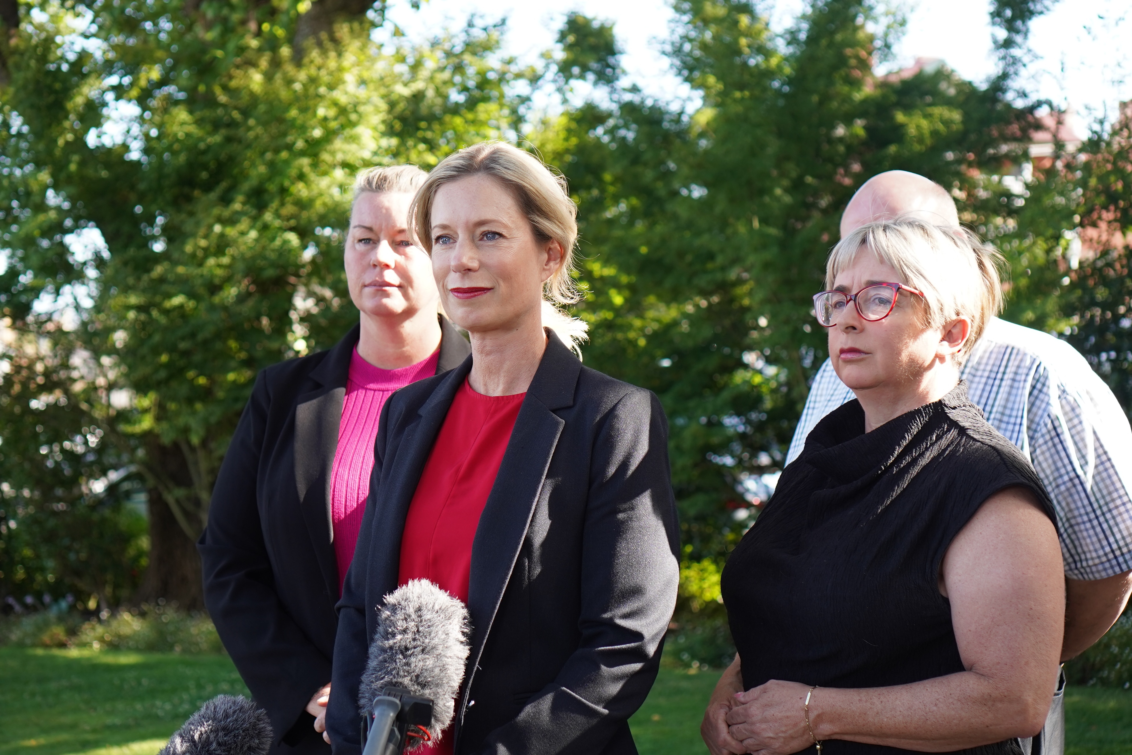 Three women, all wearing black, stand in a row. 