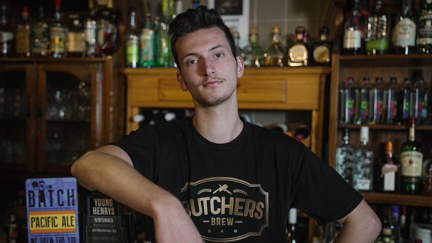 Luka Hackett stands leaning against beer taps.