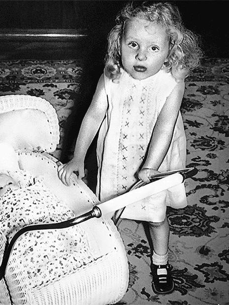 A young girl plays with a doll in a pram.