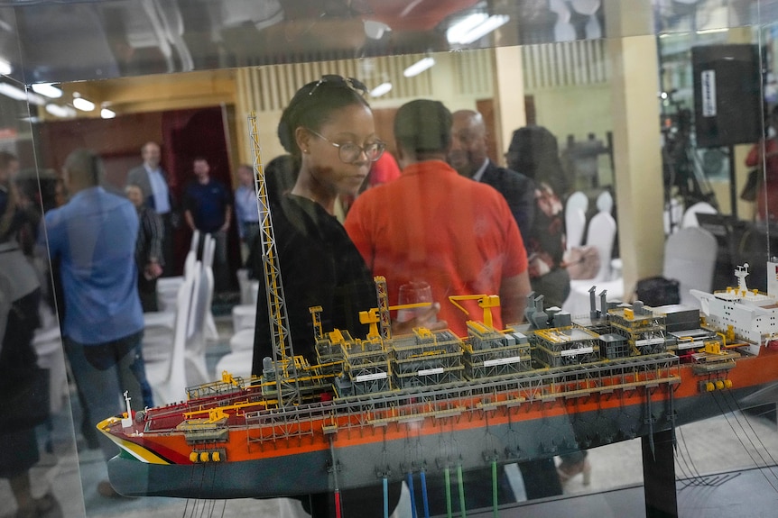 A woman looking at a model ship through a display cabinet. 