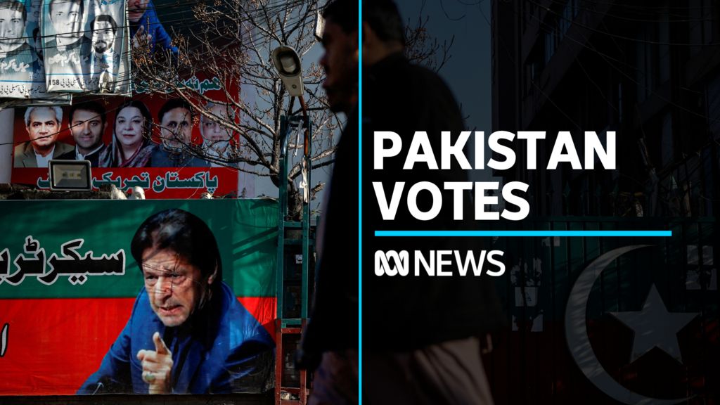 Pakistan Vote: Man walks in front of campaign poster featuring Imran Khan