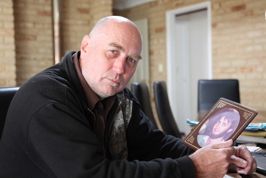 Mark Jones sits with a picture of his brother Tony Jones, who disappeared in 1982.