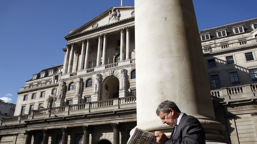 A city worker reads a newspaper opposite the Bank of England