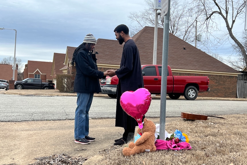 A man and woman pray at the site where Tyre Nichols was beaten, where there are toys on the ground