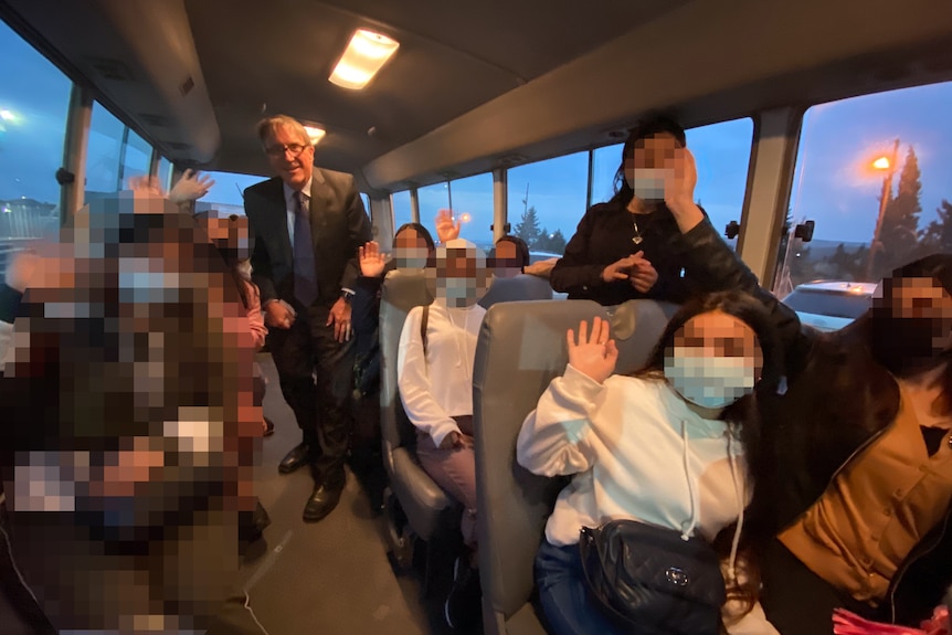 Women in face masks on a bus with a man in a suit