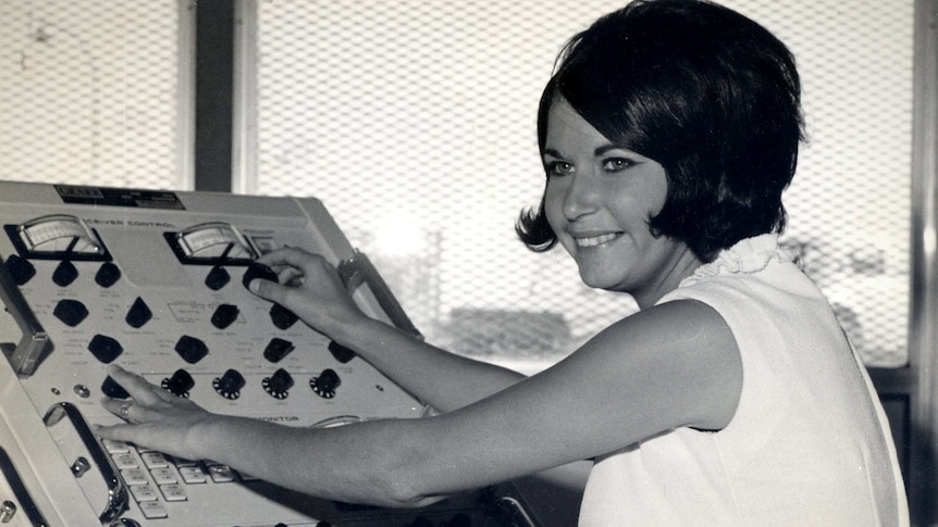 A black and white picture of Lauri Glocke smiling while working at a control panel.