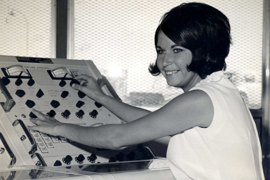 Woman sits in front of a control panel