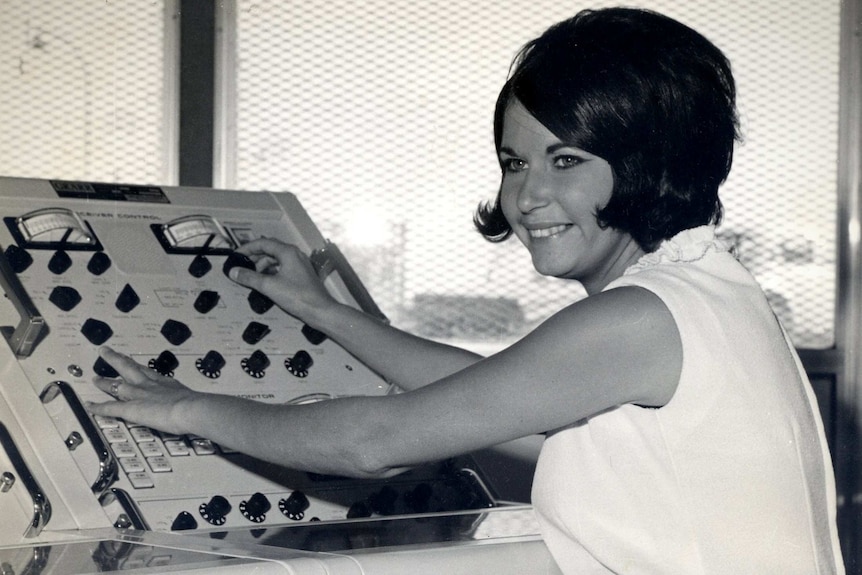 A black and white picture of Lauri Glocke smiling while working at a control panel.