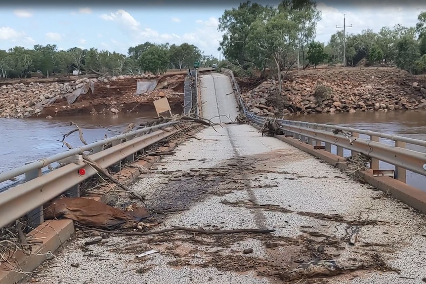 A severely damaged bridge with debris strewn over it. 