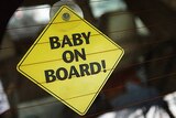 A baby on board sign in the rear window of a car to let motorists know to slow down.