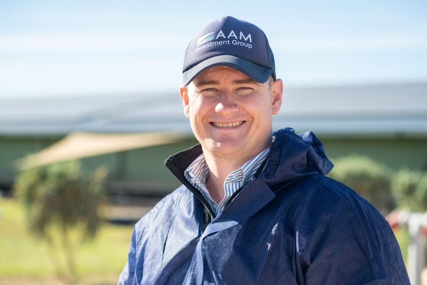 A man in a blue cap and jacket smiles at the camera.