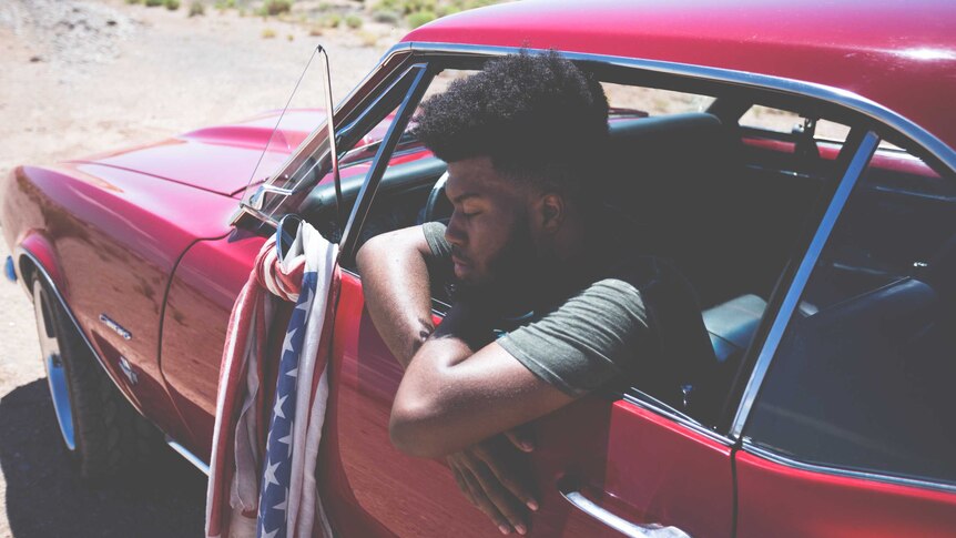 A 2017 press shot of Khalid leaning pensively out the window of a muscle car