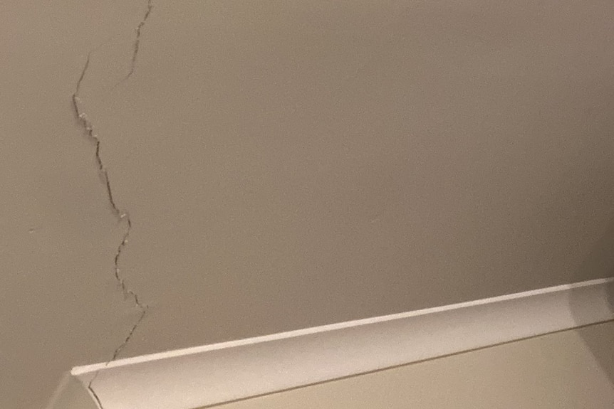 Large cracks in the plaster snake along the ceiling of a home