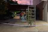 Police tape marking a crime scene with police officers in the background
