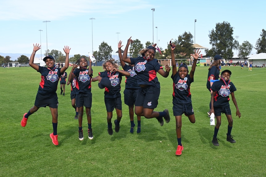 Victorious junior softballers from the APY Lands jump for joy.