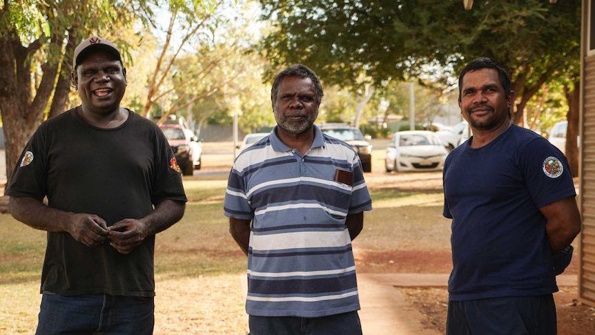 Three men smile at the camera